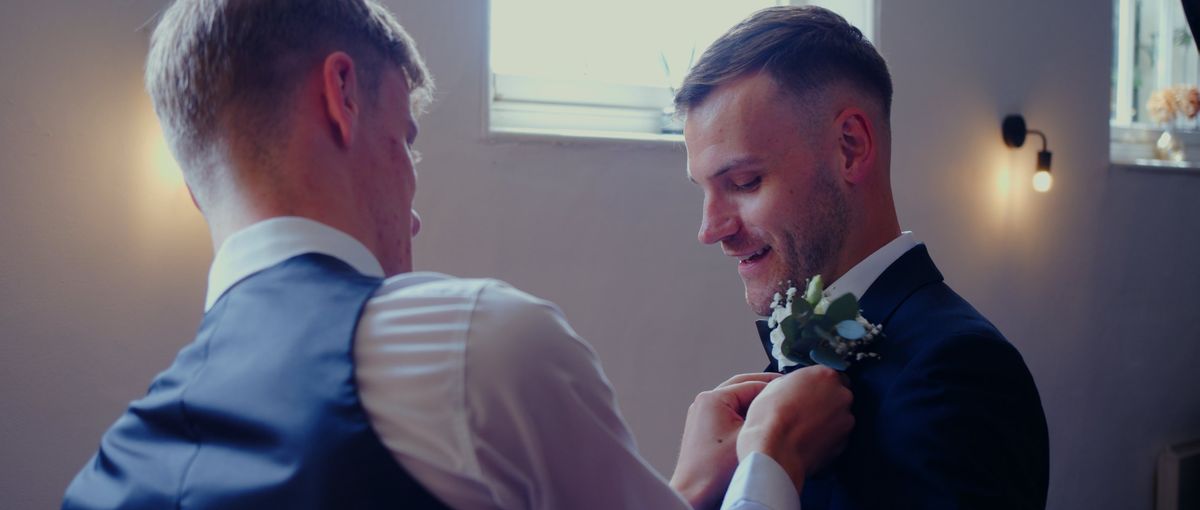 A groomsman pinning the groom's buttonhole
