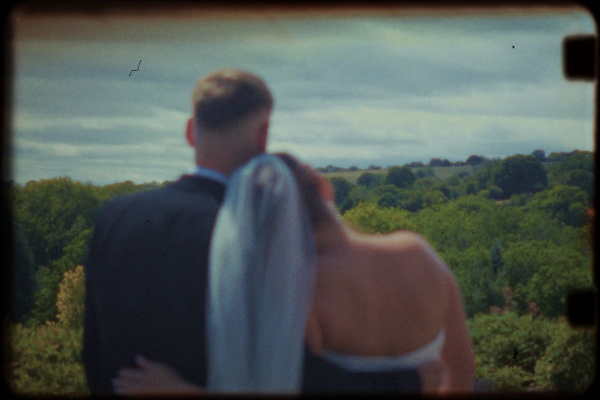 Super 8 style frame of the couple looking out over the countryside